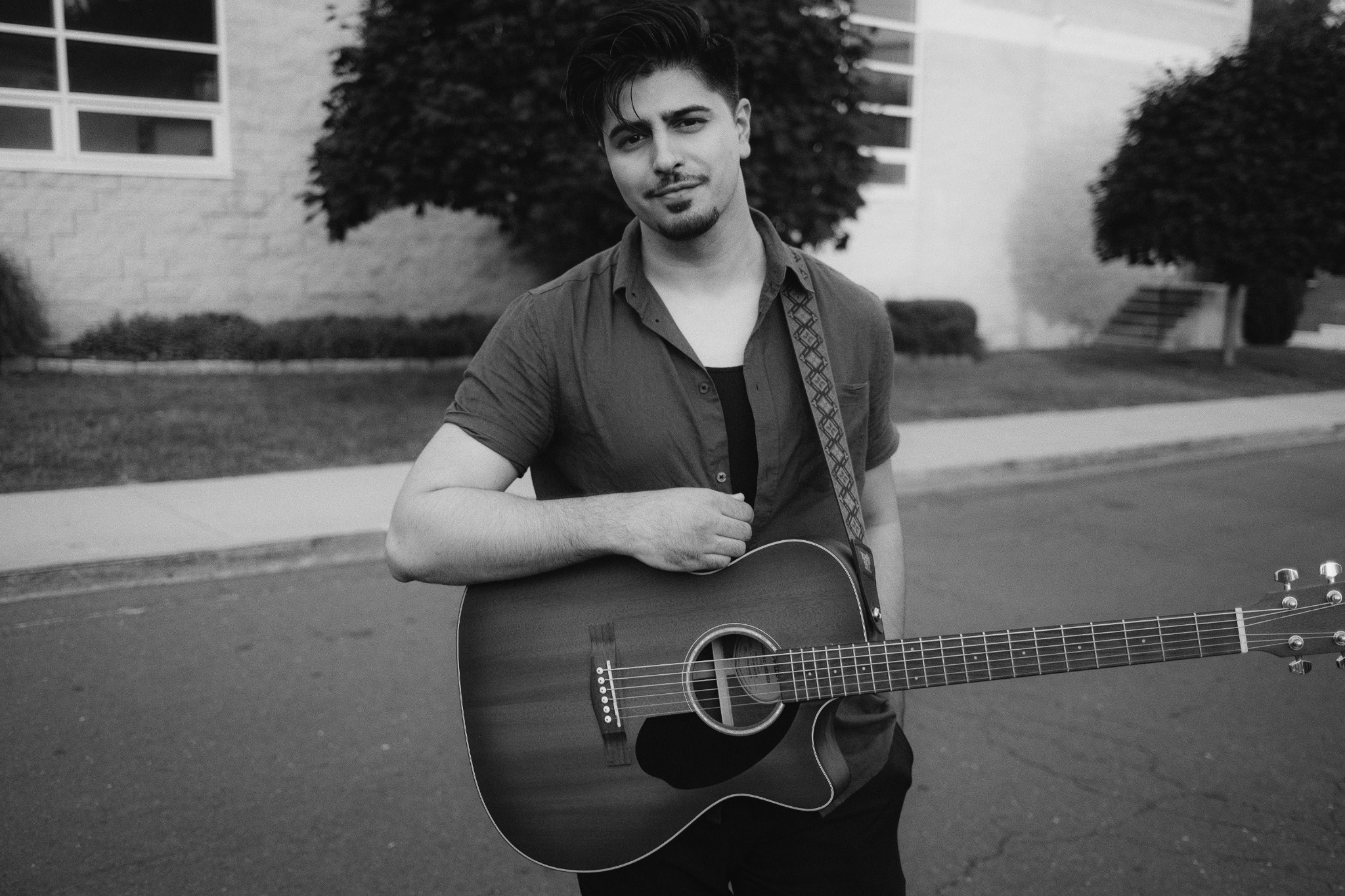Alman Nusrat holding an acoustic guitar outdoors